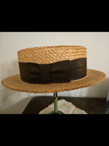 Large 1920s straw boater hat with a wide, brown silk grosgrain ribbon band.