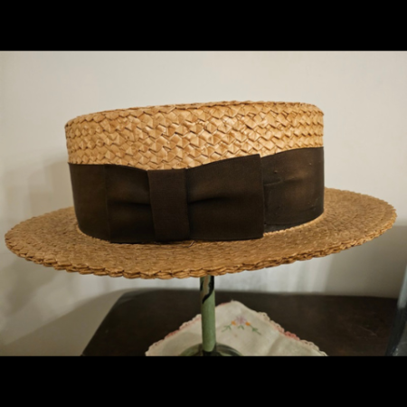 Large 1920s straw boater hat with a wide, brown silk grosgrain ribbon band.